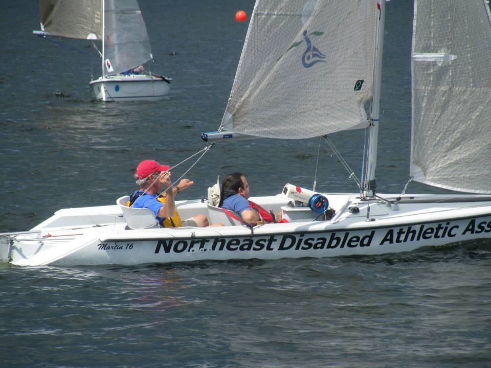 Sailor and crew sail an adaptive Martin 16