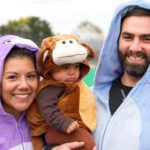 Two students pose with an adorable child in a monkey costume