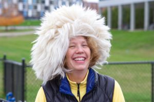 Nancy Gell smiles while wearing a hat that looks like white, poofy hair