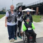 NDAA board members Patrick Standen and Lee Weltman pose with their family. Lee wears a skeleton costume, eerie skeleton makeup, and a creepy Undertaker hat