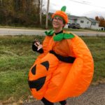 A woman in a pumpkin costume smiles for the camera