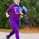 A runner dressed in purple smiles as she passes