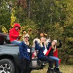 Friends (and their dog) in costume pose in the back of a truck