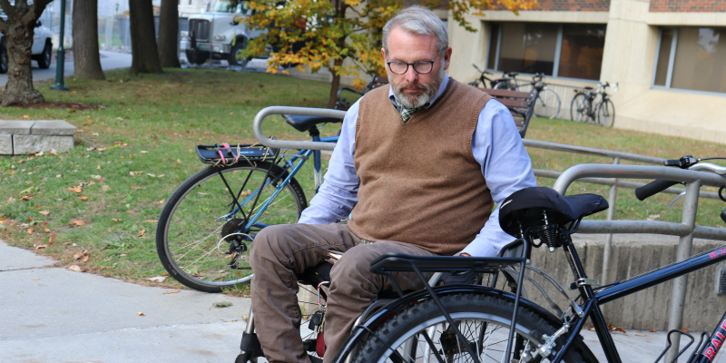 Patrick maneuvers his wheelchair around a bike chained to the side of a wheelchair ramp