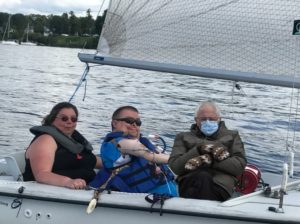 Bernie Sanders (wearing a winter coat, homemade mittens, and a hospital mask from a widely-memed photo at Joe Biden's inauguration) photoshopped next to two sailors in our Martin 16 sailboat